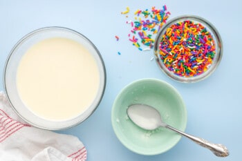 melted white chocolate and coconut oil in a glass bowl and sprinkles in another glass bowl