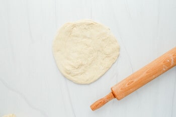 rolled out pizza dough with rolling pin