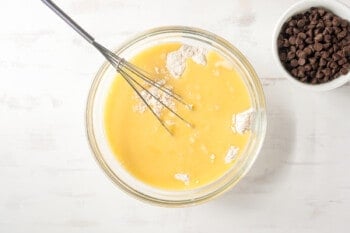 wet and dry ingredients in a glass bowl with a whisk