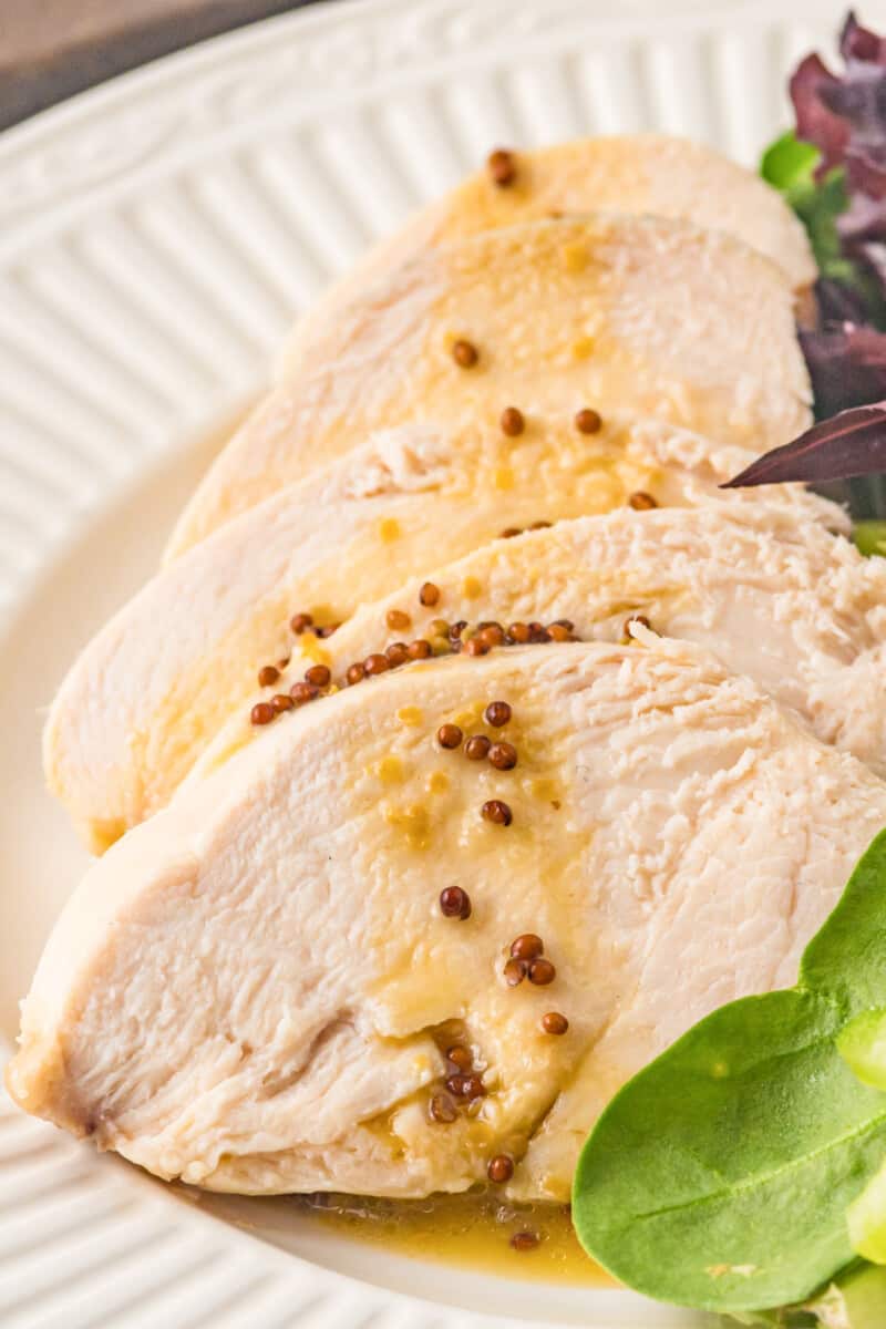 sliced poached chicken breast on a white plate