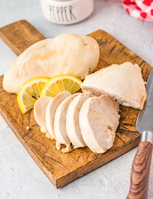 sliced poached chicken breasts on a wood cutting board