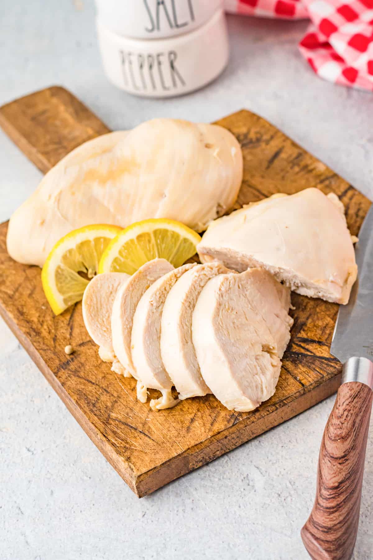 sliced poached chicken breasts on a wood cutting board