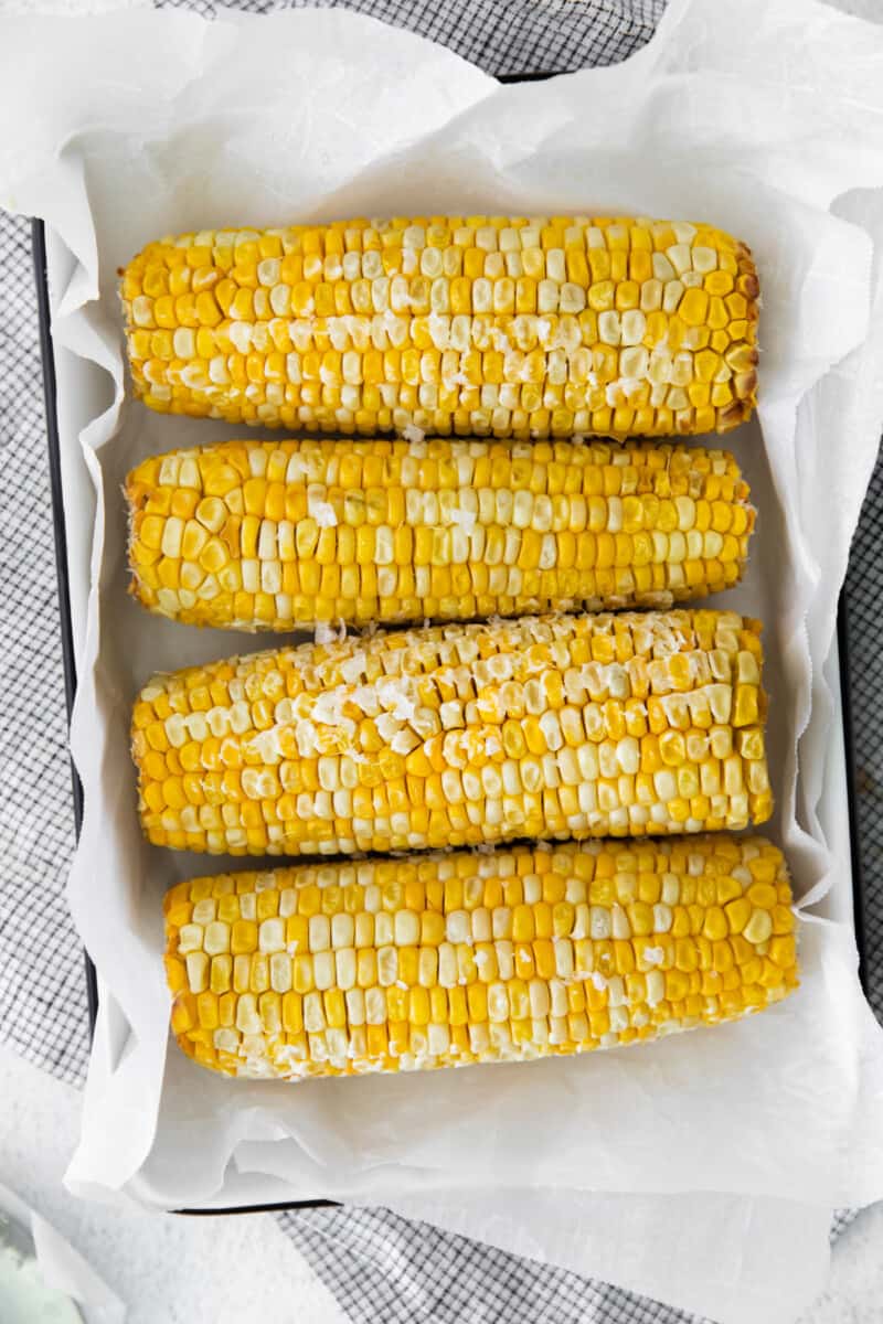 overhead image of 4 ears of corn on the cob on a serving platter