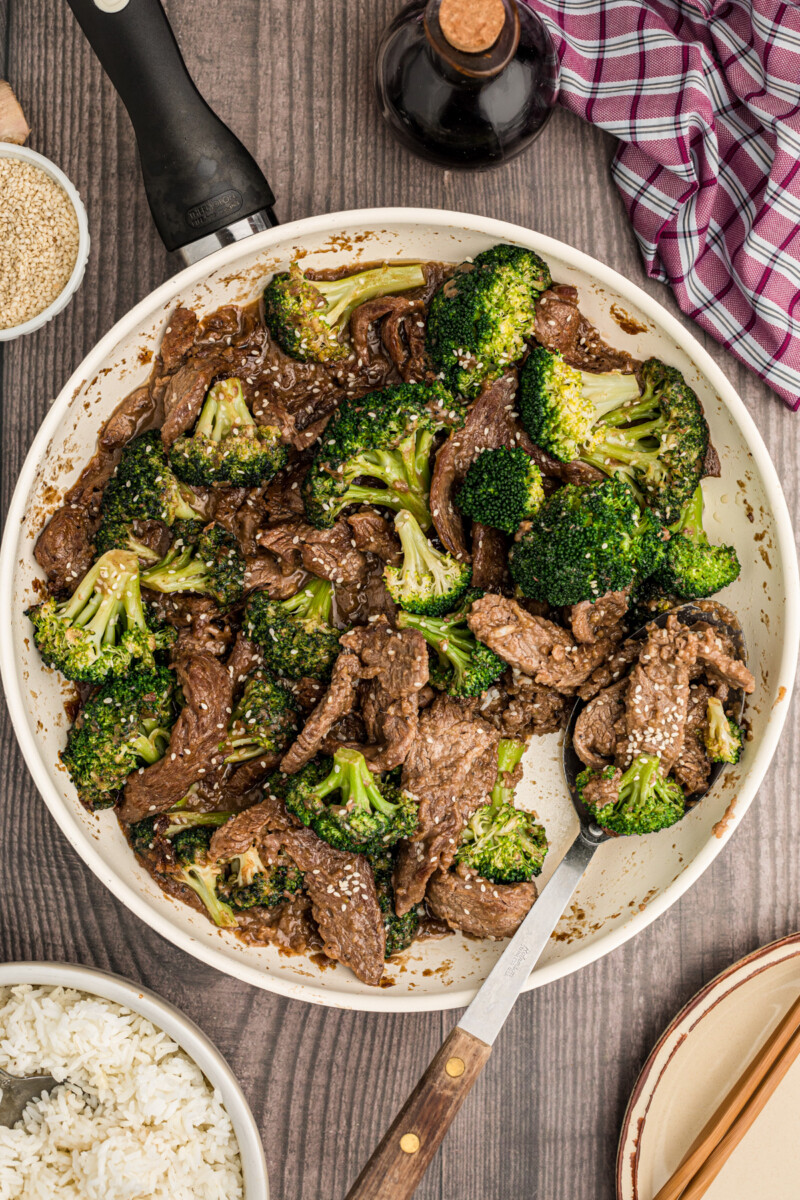 beef and broccoli in a skillet with a serving spoon