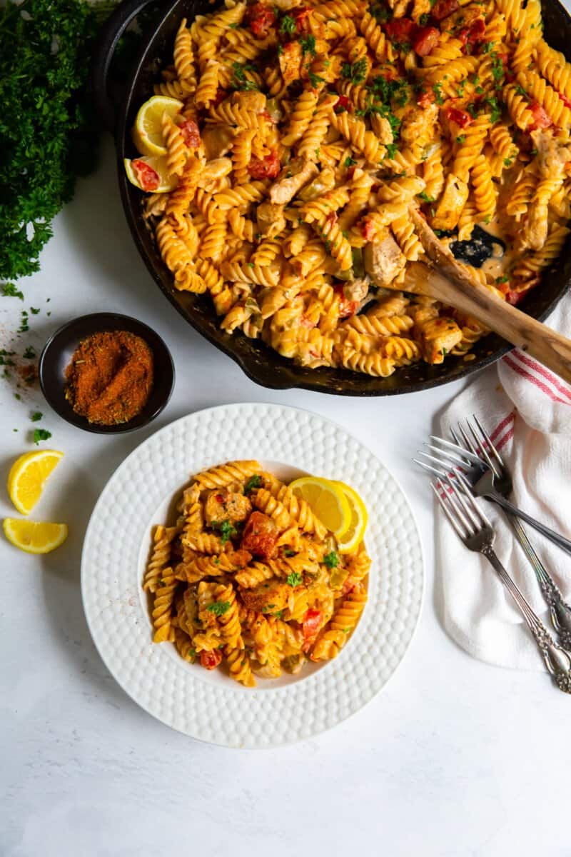 cajun chicken pasta in a skillet and a serving on a white plate