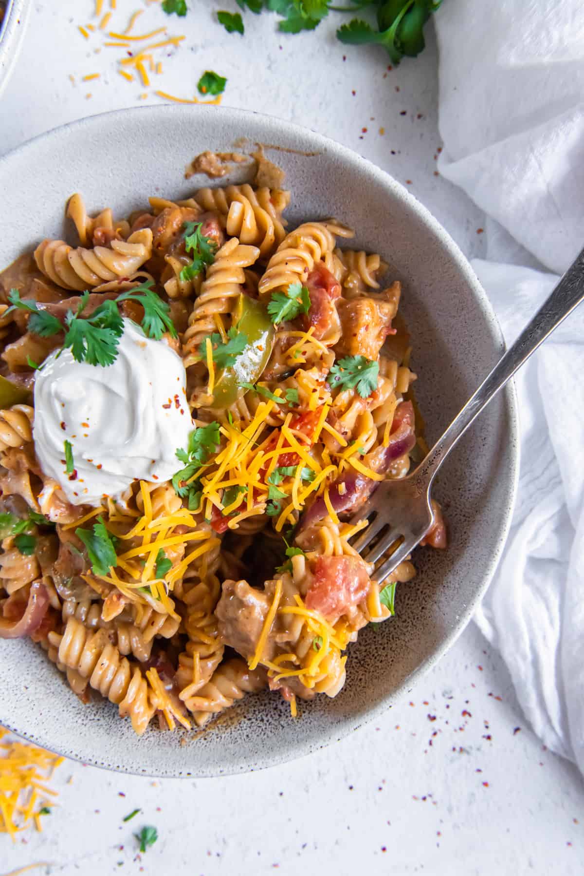 chicken fajita pasta in a white bowl with a fork