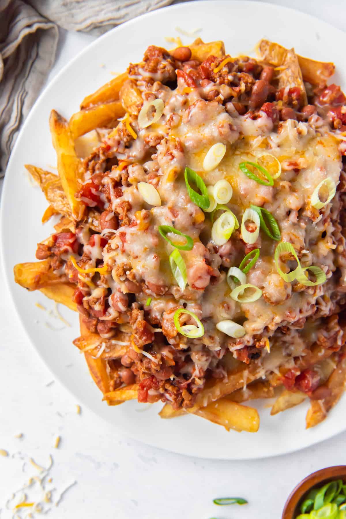 overhead image of chili cheese fries on a white plate