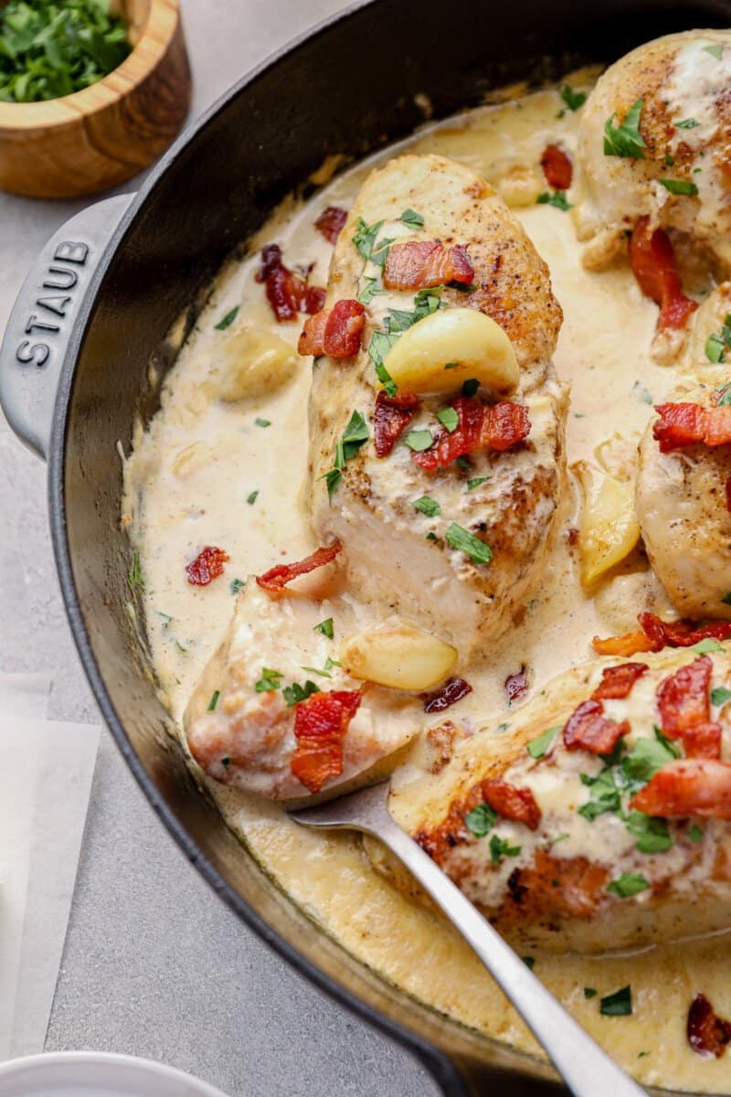 creamy garlic chicken with bacon in a skillet with a serving fork