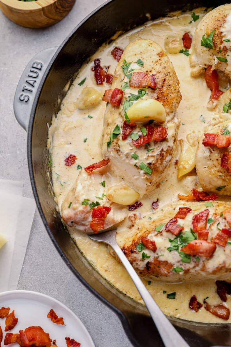 creamy garlic chicken with bacon in a skillet with a serving fork