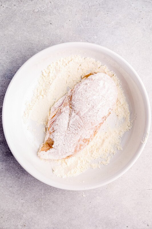 chicken breast coated in flour on a white plate