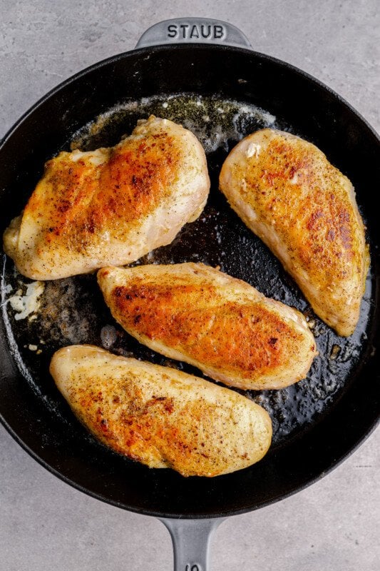 4 chicken breasts in a skillet after cooking
