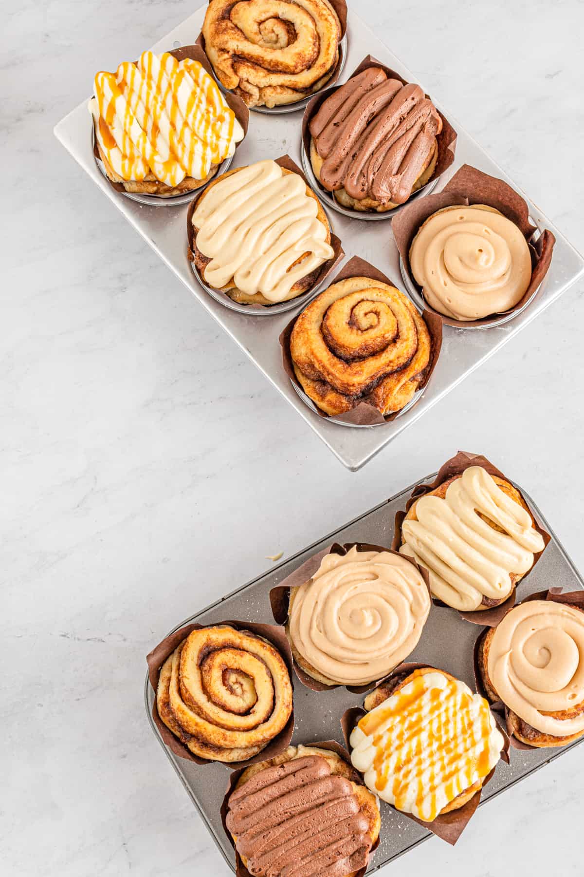 bakery style cinnamon rolls on white marble.