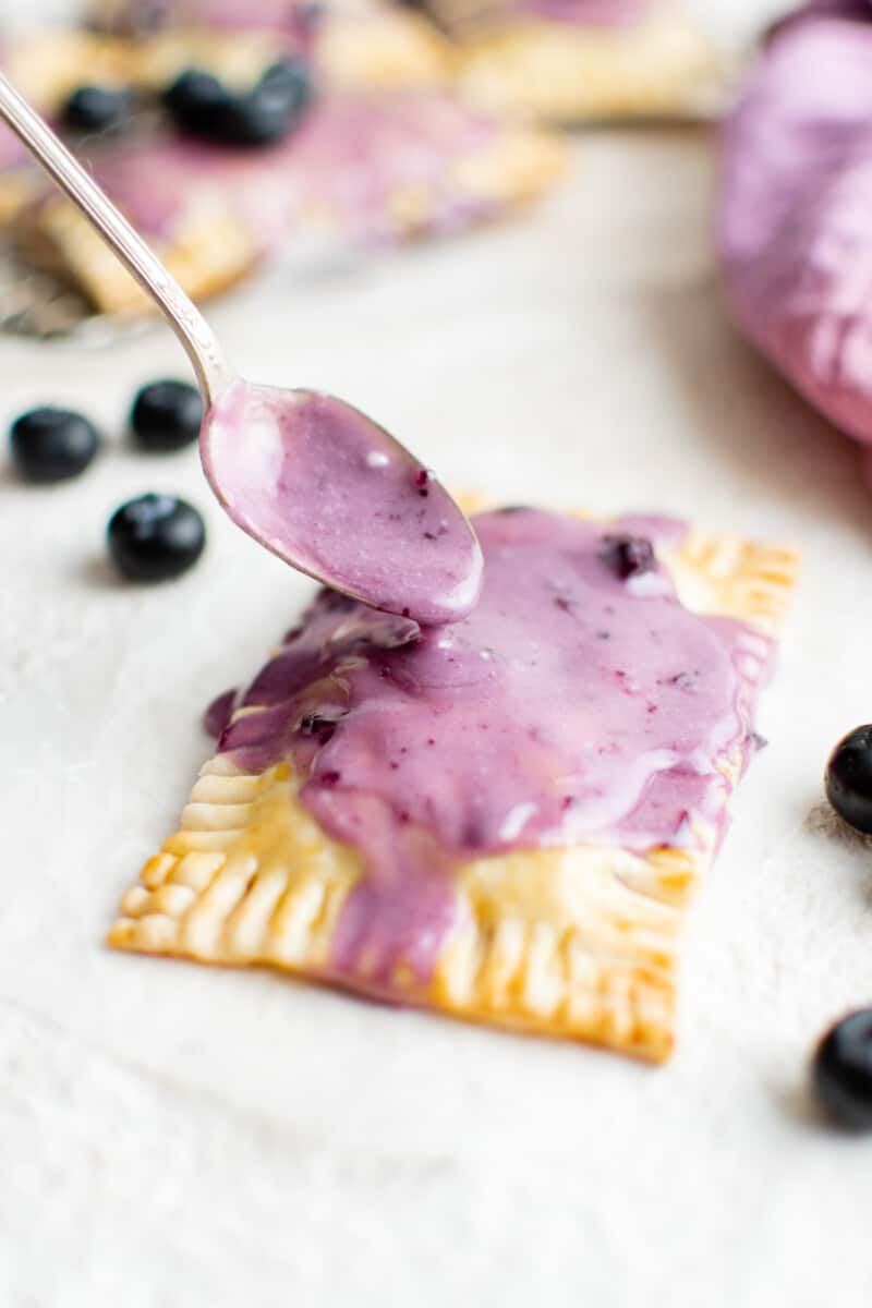 icing poured on a blueberry pop tart with a spoon.