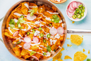 Overhead view of chilaquiles in a sauté pan with radishes and jalapeños.