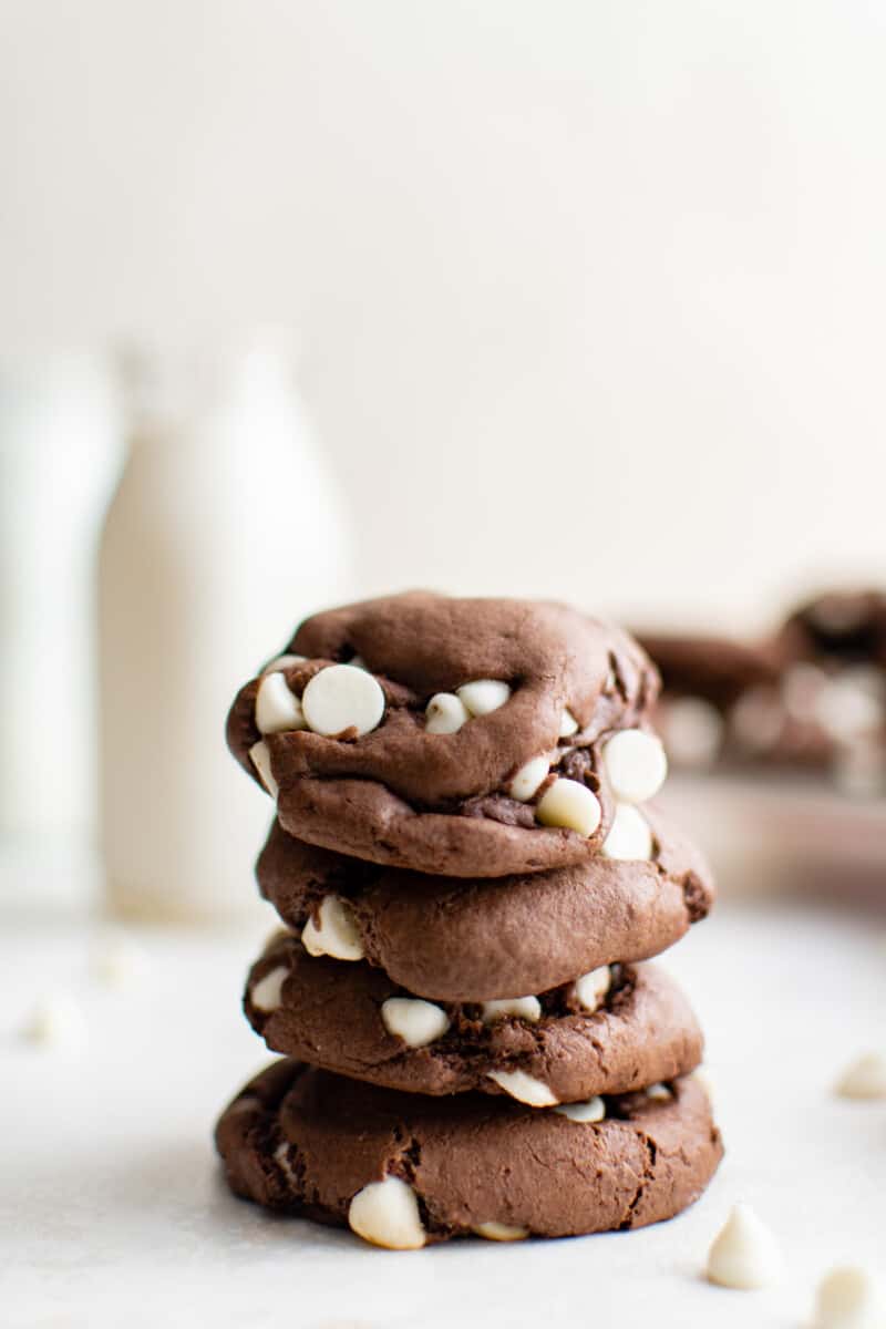 5 biscoitos de mistura de bolo de chocolate empilhados na frente de uma jarra de leite.