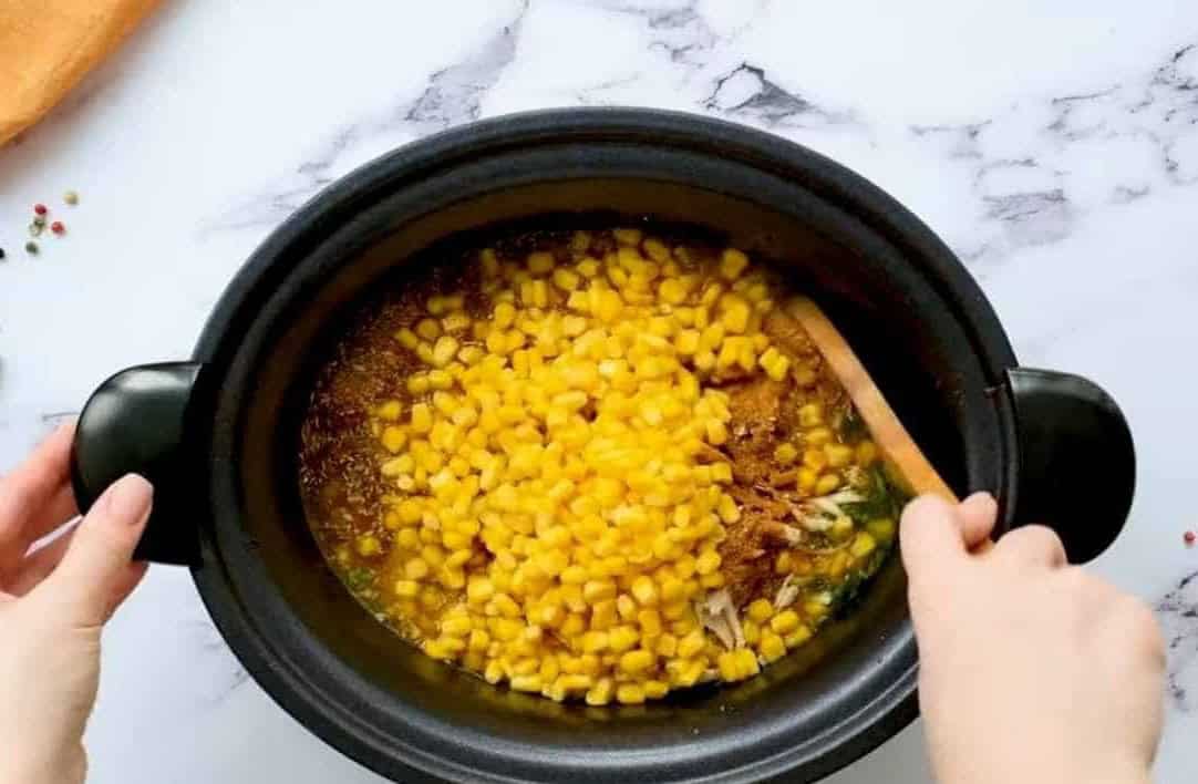 Adding beans and corn to the crockpot.