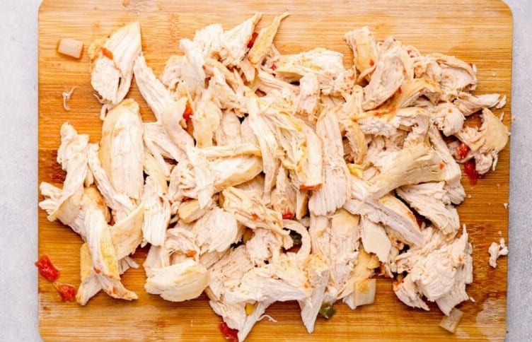 Shredded chicken on a wooden cutting board.