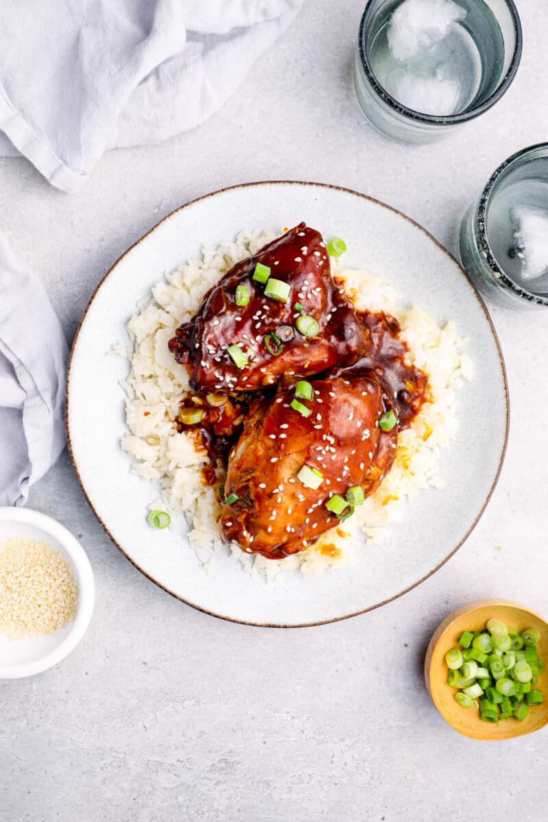 overhead image of honey garlic chicken on top of rice on a white plate