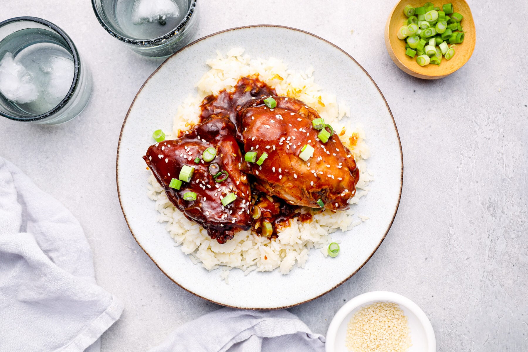 overhead image of honey garlic chicken on top of rice on a white plate