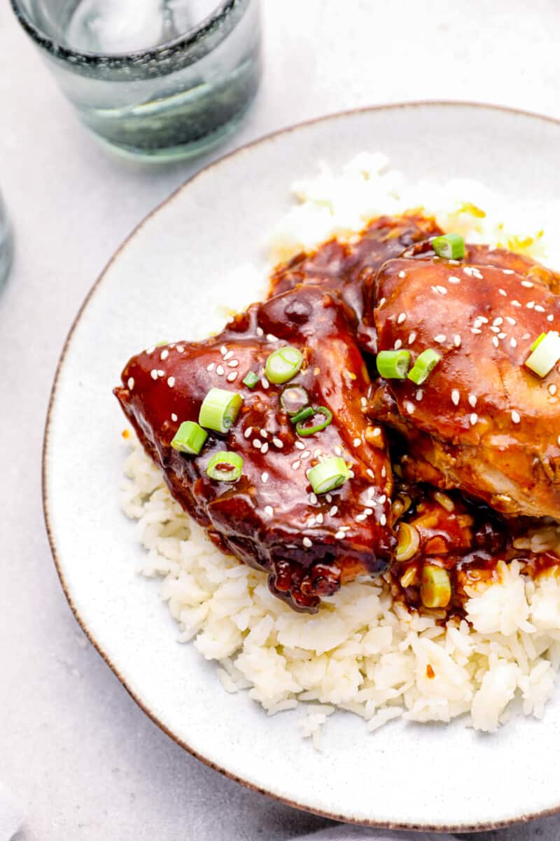 honey garlic chicken on top of rice on a white plate