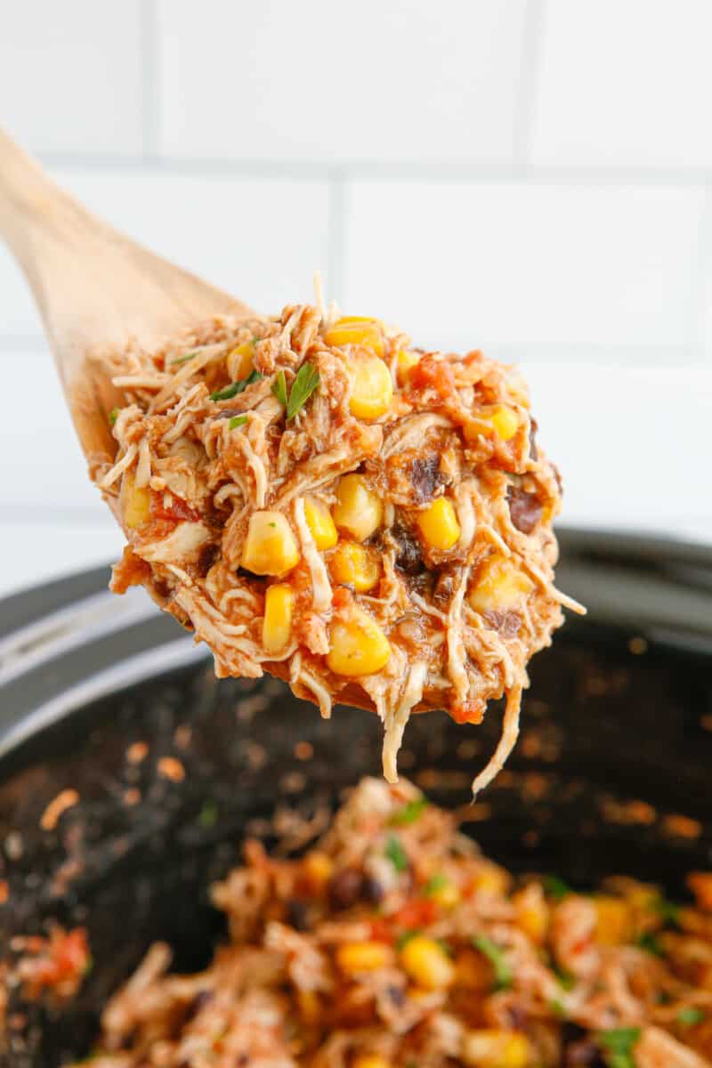 close up of crockpot mexican shredded chicken on a wooden spoon.