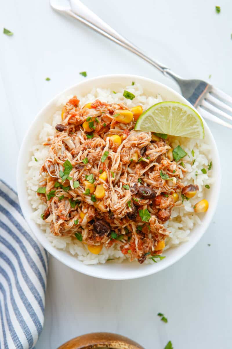 overhead view of crockpot mexican shredded chicken over rice in a white bowl.