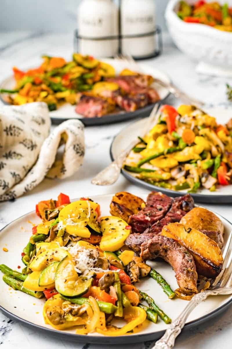 servings of sauteed vegetables on white plates with forks