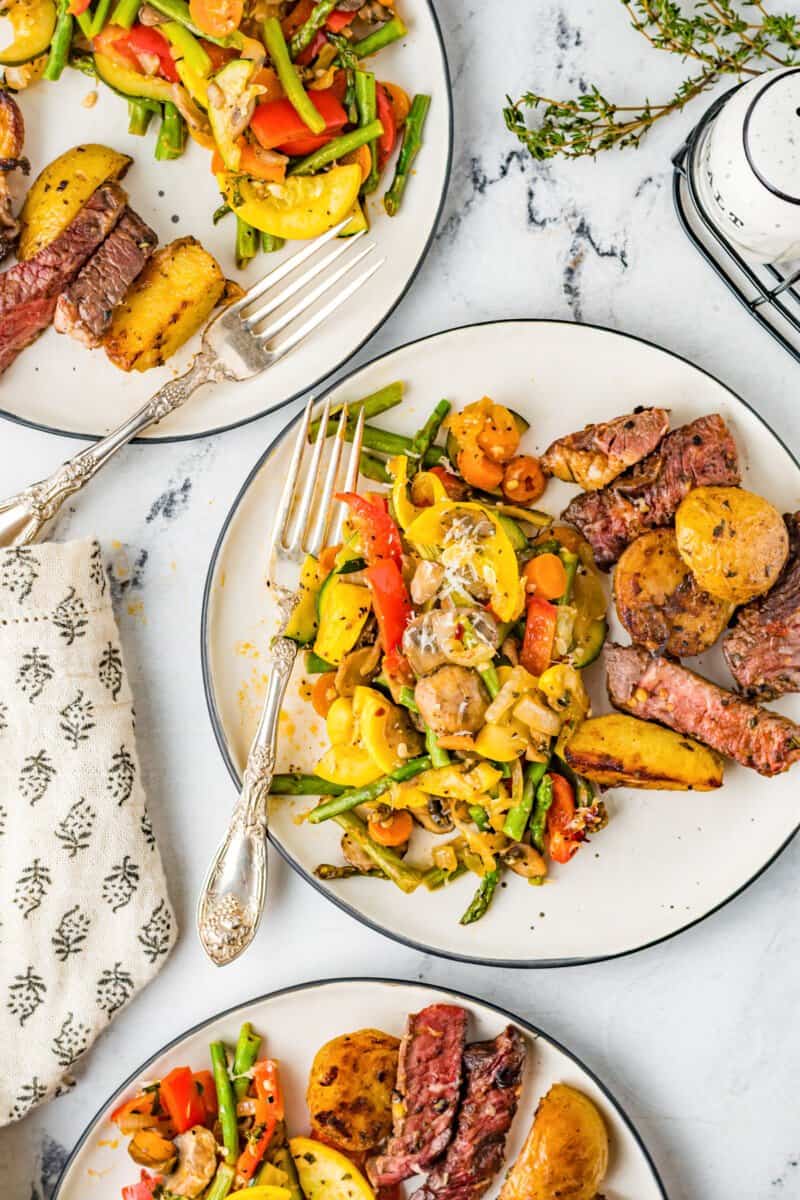 overhead image of servings of sauteed vegetables on white plates with forks