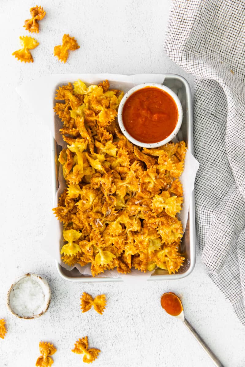 overhead view of garlic parmesan pasta chips on a serving tray with marinara sauce.