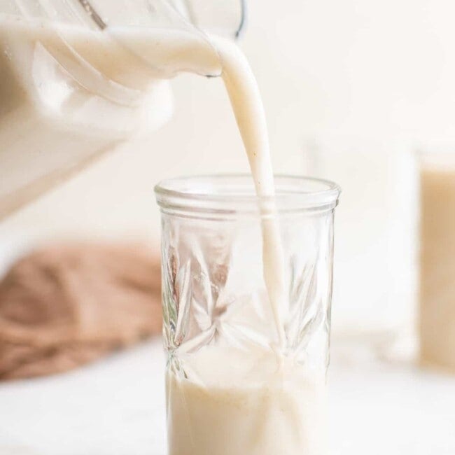 pouring oat milk into a glass