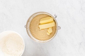 A bakery-style cinnamon roll preparation with a bowl of butter and flour.