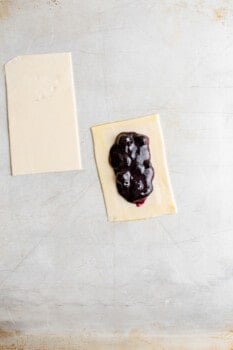 blueberry filling on a rectangle of pie crust next to a second rectangle of pie dough.