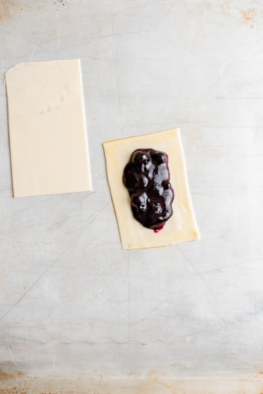 blueberry filling on a rectangle of pie crust next to a second rectangle of pie dough.