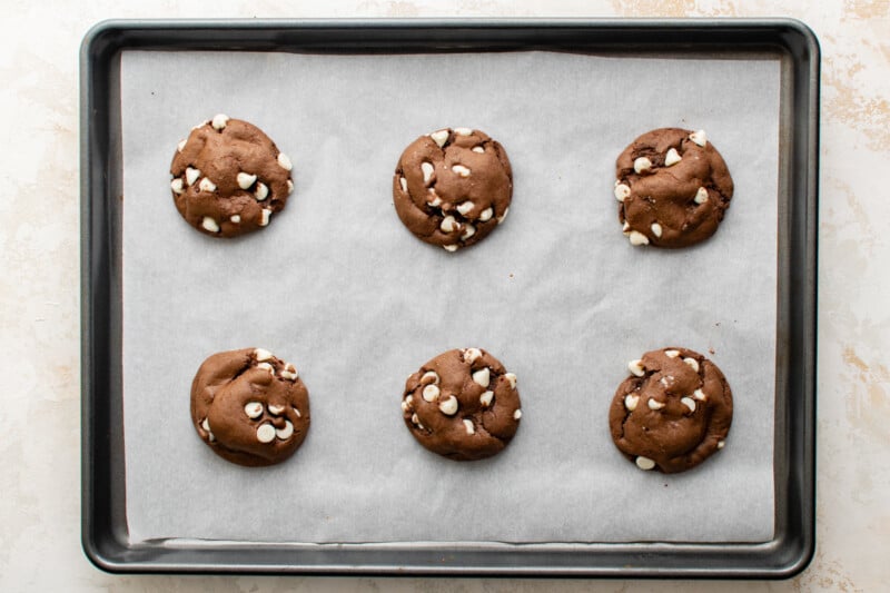6 baked chocolate cake mix cookies on a baking sheet.