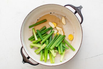 garlic ginger green onions and sesame oil in a black pot.