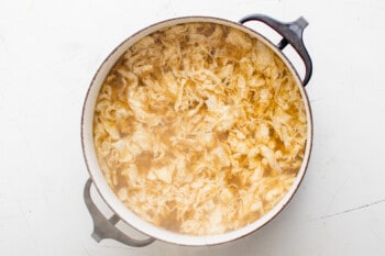 overhead view of egg drop soup in a black pot.