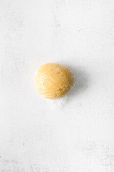 ball of homemade pasta dough on a white work surface.