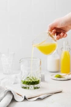 pineapple juice poured into a glass of matcha.