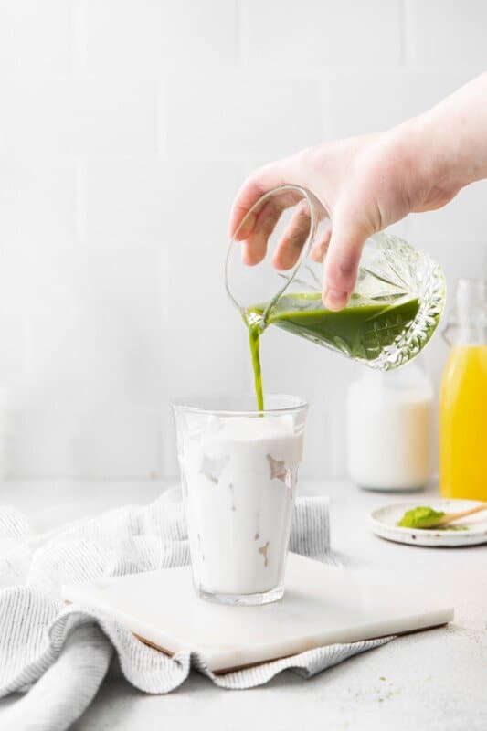 matcha poured over a glass of coconut milk.