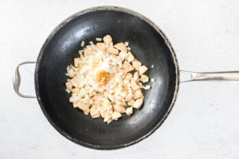 cooked chicken in a wok with onion, garlic, and salt.