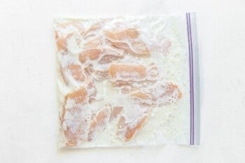 raw chicken fingers in a sealed zip top bag with marinade.