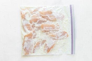 raw chicken fingers in a sealed zip top bag with marinade.