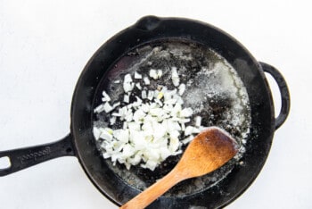 garlic and onions in a skillet with a wooden spoon.