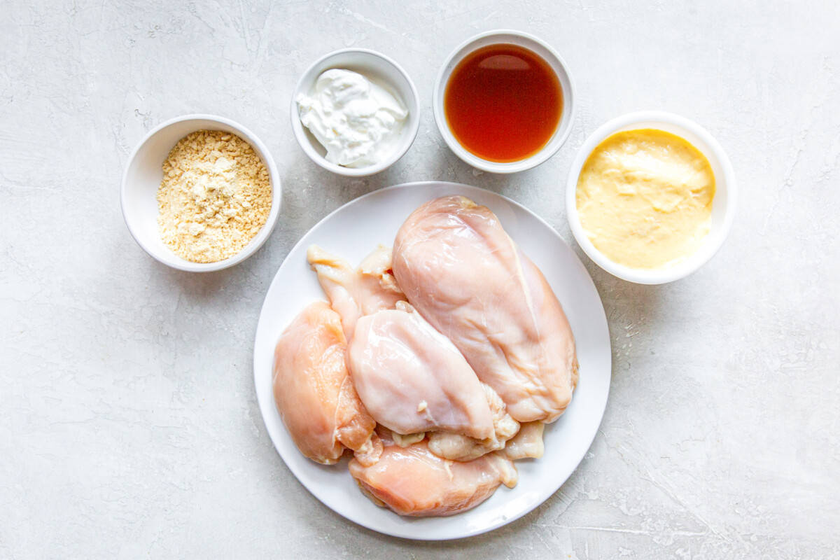 overhead view of raw chicken and various liquids in individual bowls.