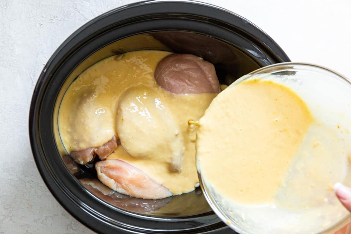 gravy poured over raw chicken breasts in a crockpot.