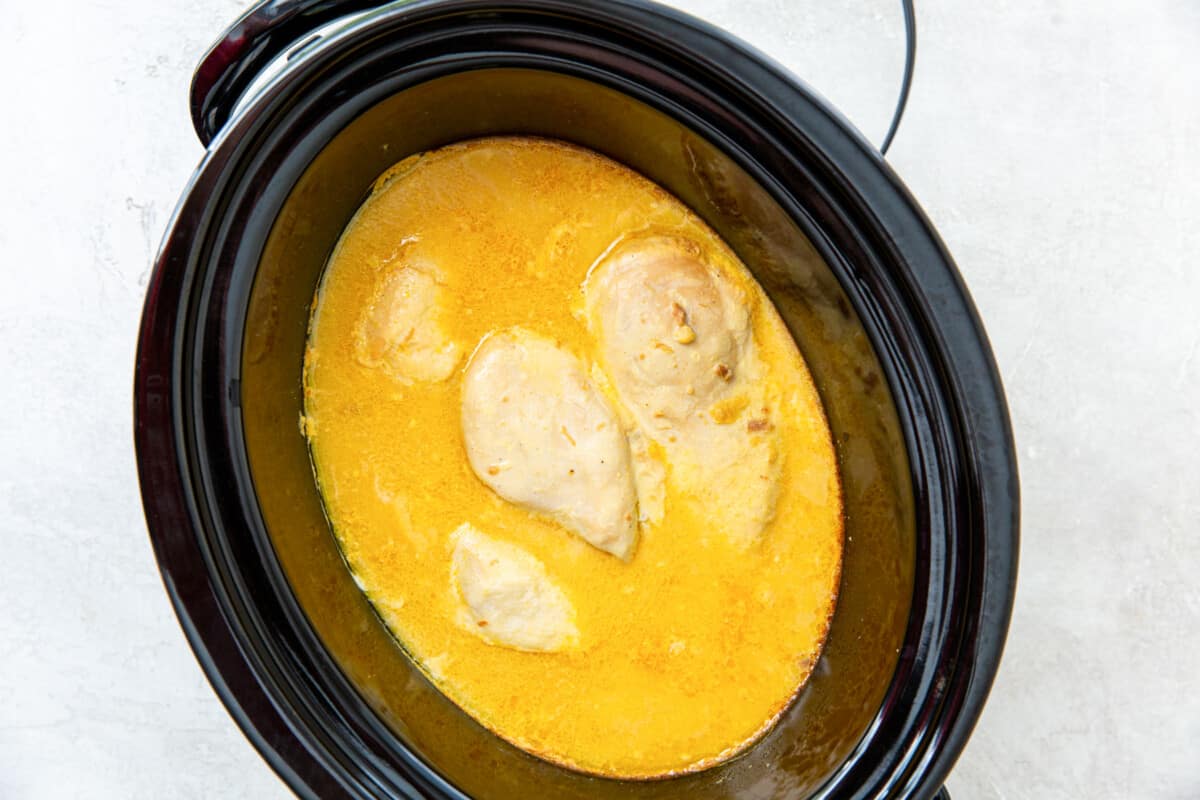 cooked chicken in yellow sauce in a crockpot.