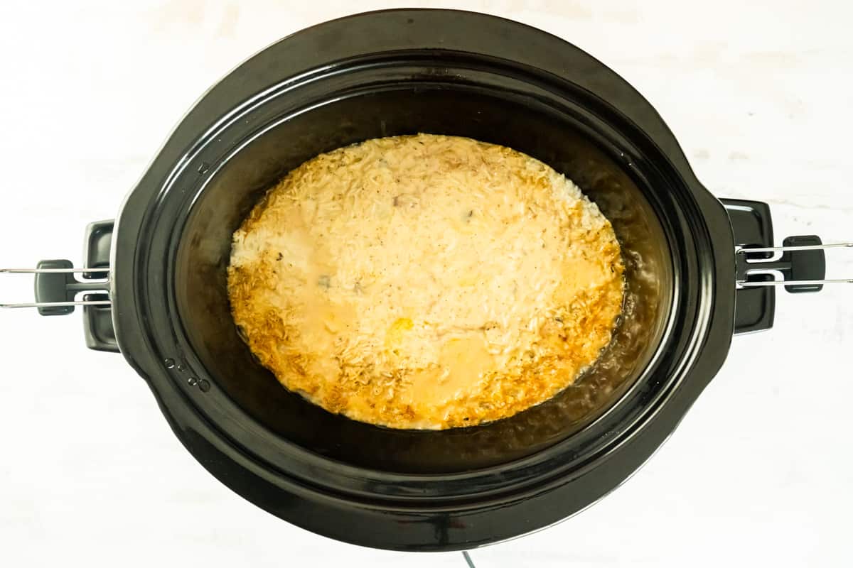 Uncooked crockpot chicken and rice in the crockpot.