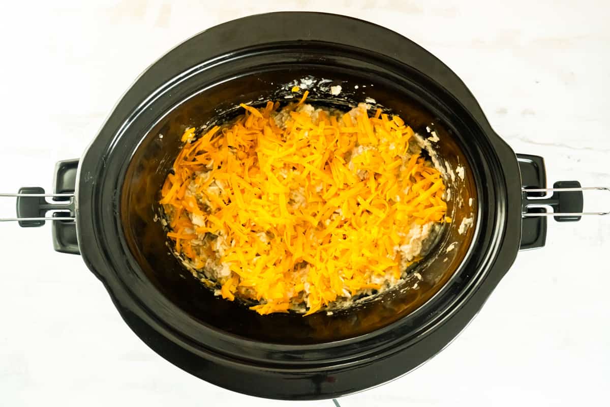 Cheese sprinkled over the chicken and rice in a crockpot.
