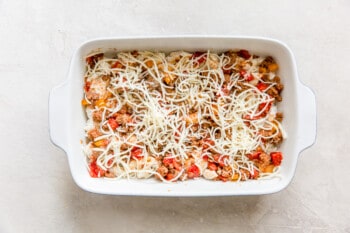 creamy shell noodles topped with hamburger mixture and shredded cheese in a white baking dish