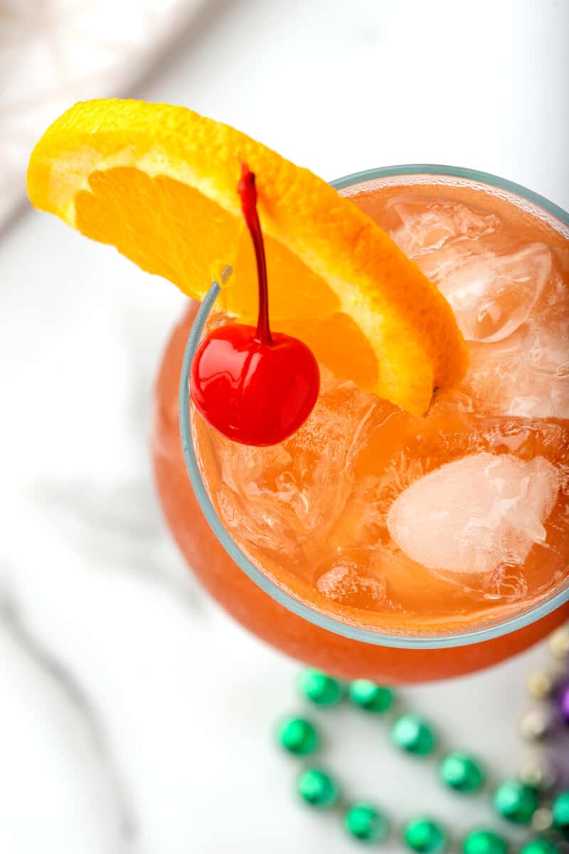 overhead image of hurricane cocktail in a glass garnished with an orange slice and a cherry